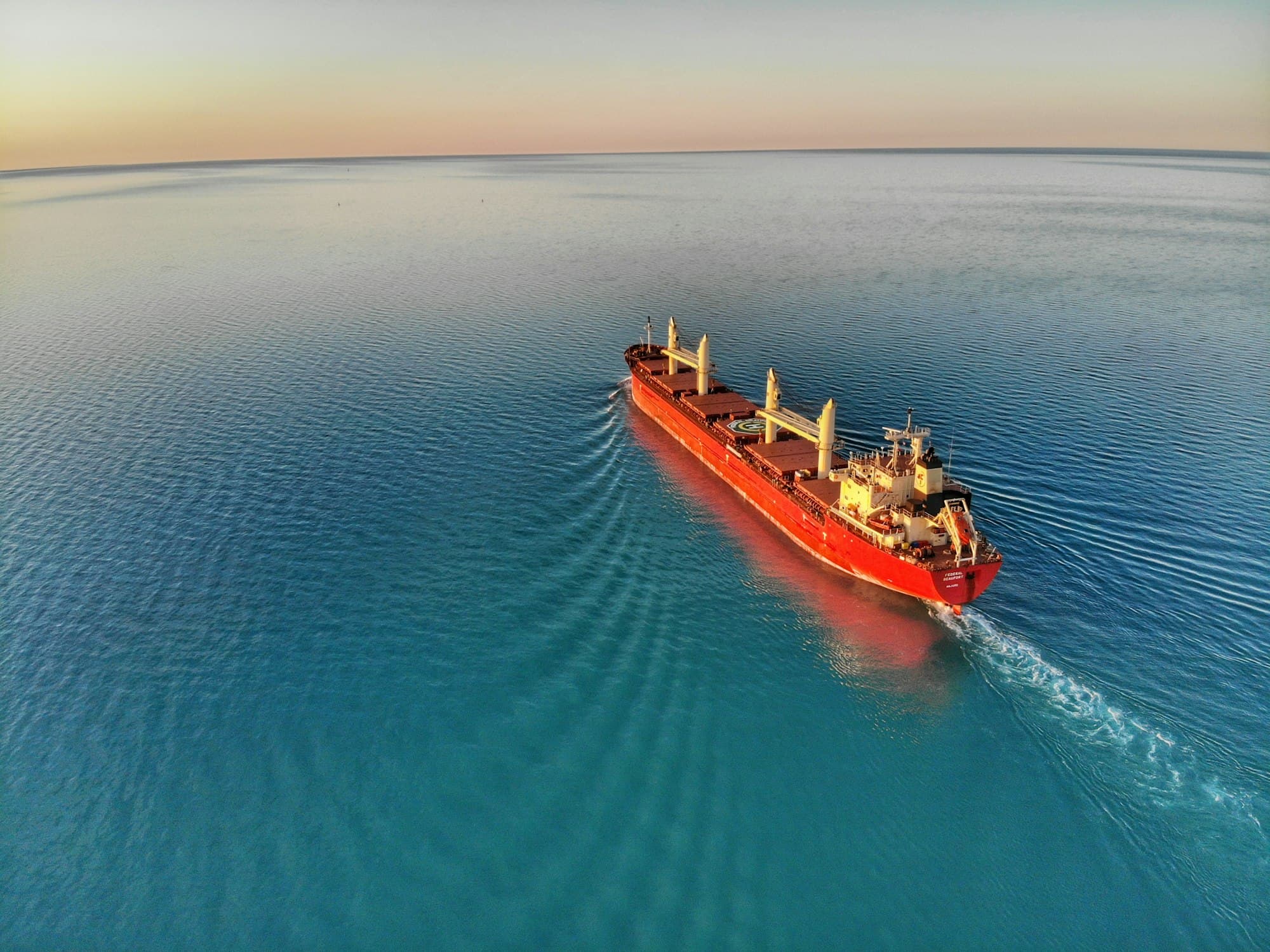 Aerial view of a bulk carrier ship sailing across calm open sea