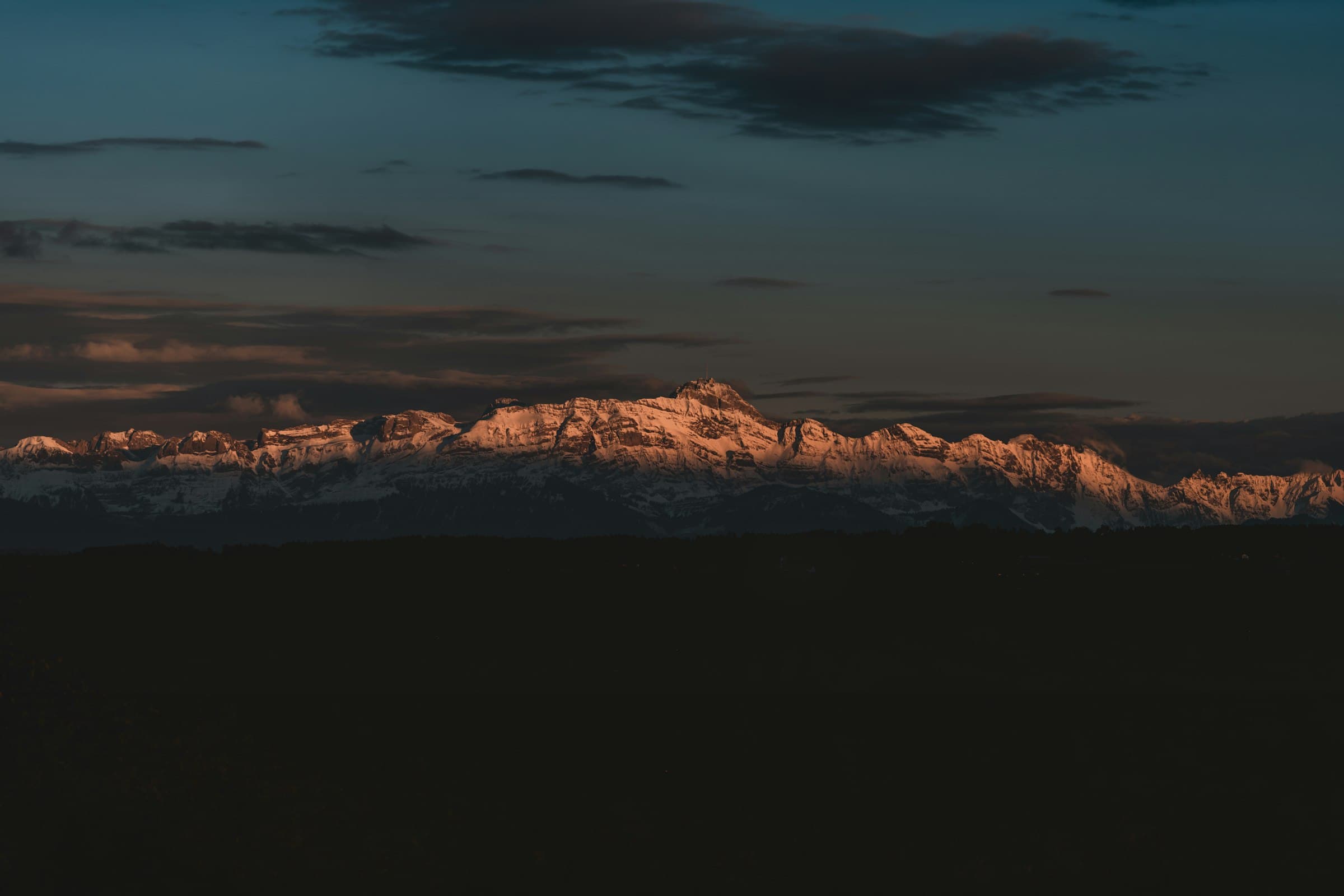 Mountain peaks glowing orange at sunset under a dark sky